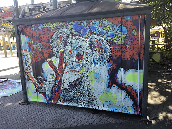 Colorful heavy-duty industrial curtain featuring a vibrant koala graphic, installed in a commercial outdoor setting for durable enclosure.