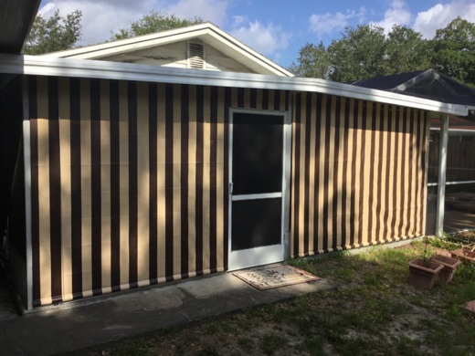 Striped heavy-duty industrial curtain in beige and black, enclosing a residential structure for added protection and privacy.