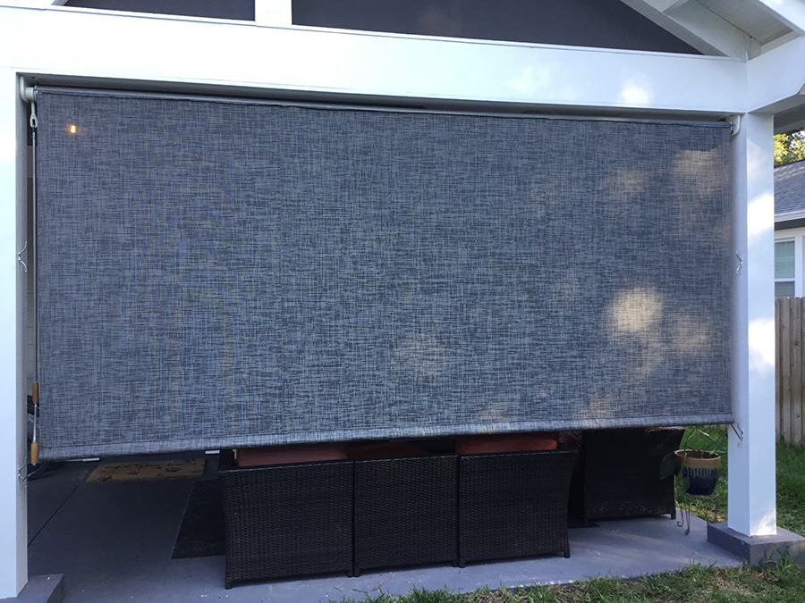 Gray heavy-duty industrial curtain providing shade and privacy for a covered outdoor residential patio area.