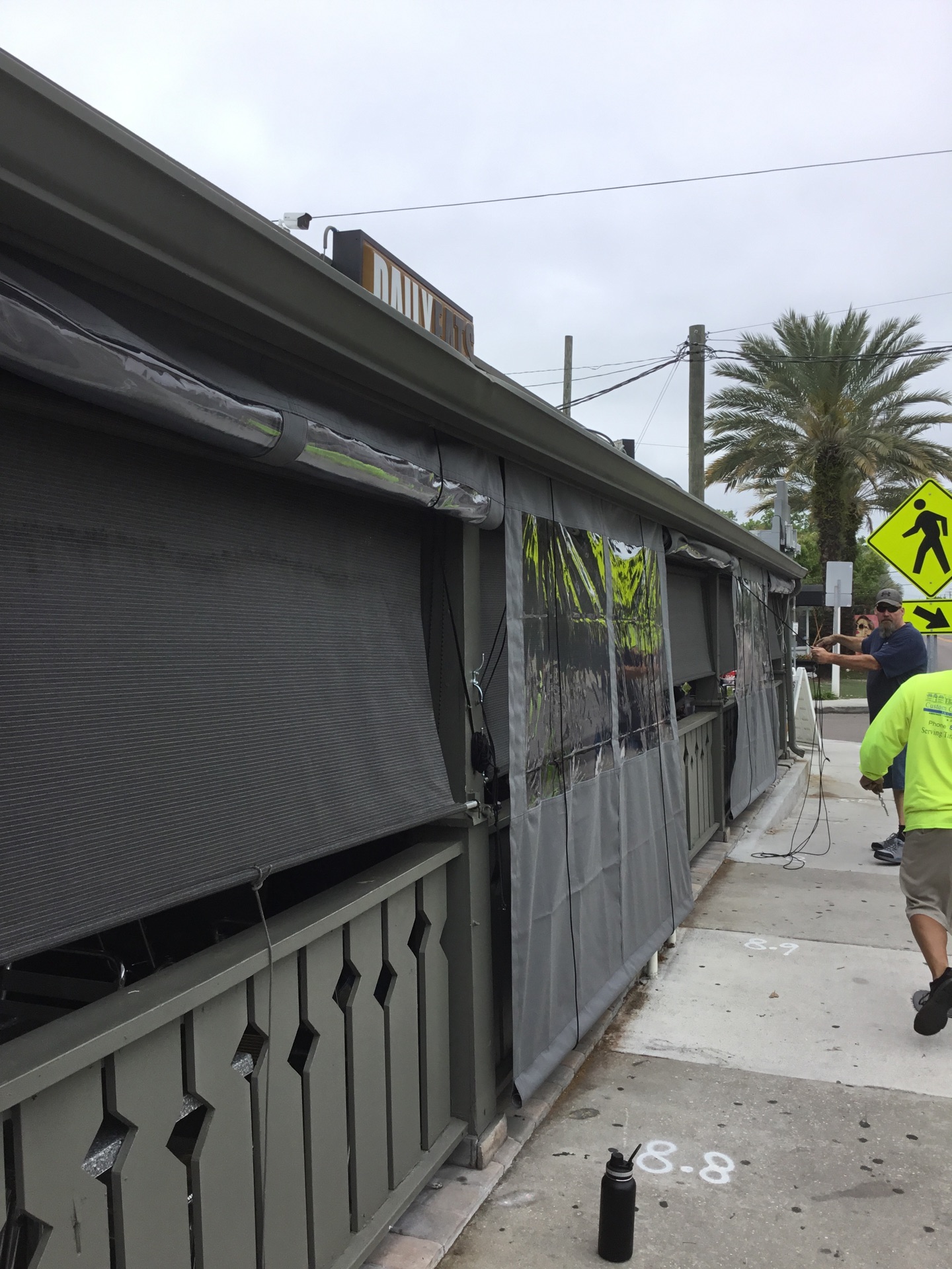 Heavy-duty industrial curtains with clear vinyl panels and gray fabric, installed on a commercial outdoor patio for weather protection.