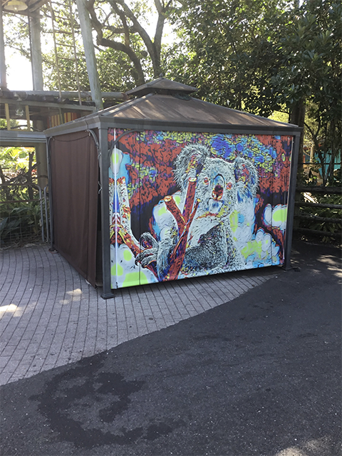 Heavy-duty industrial curtain with vibrant koala graphic, set in a commercial outdoor area with a sturdy metal frame and brown side panels.