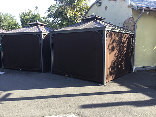 Brown heavy-duty industrial curtains enclosed in sturdy metal-framed structures, ideal for outdoor commercial or industrial use.