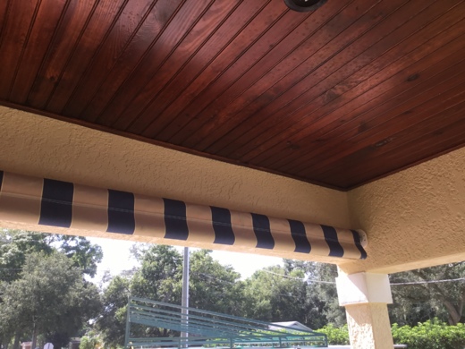 Striped heavy-duty industrial curtain in beige and navy, installed under a wooden ceiling in an outdoor commercial setting.