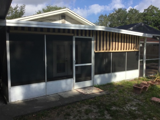 Striped yellow and black heavy-duty industrial curtain installed on a screened residential patio, providing shade and privacy.