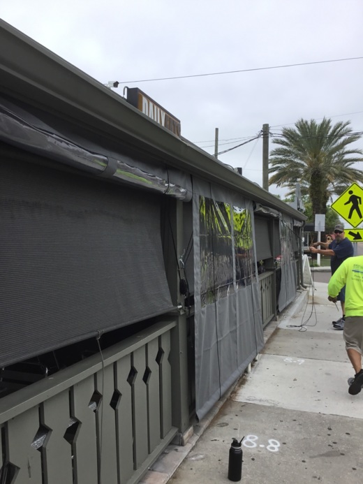 Heavy-duty industrial curtains with clear vinyl panels and gray fabric sides installed on a commercial outdoor structure in Tampa, Florida.