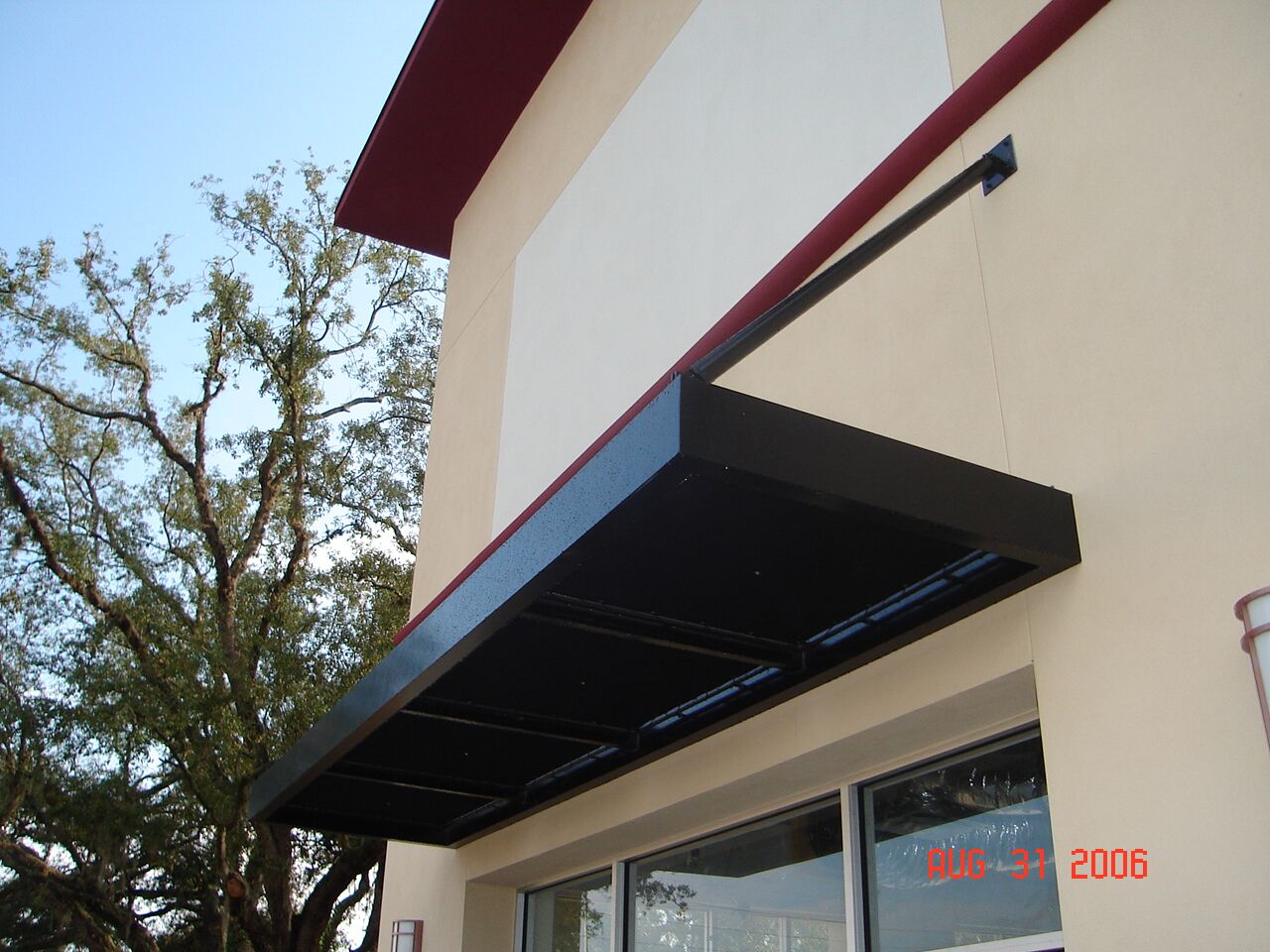 Black metal awning with a sleek, durable design installed on a commercial building, providing shade and weather protection.