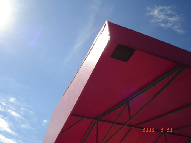 Red heavy-duty industrial curtain with sturdy metal framing, designed for outdoor use under a clear blue sky.