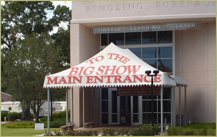 White custom entrance awning with bold red lettering reading "TO THE BIG SHOW MAIN ENTRANCE," set outside a commercial building.